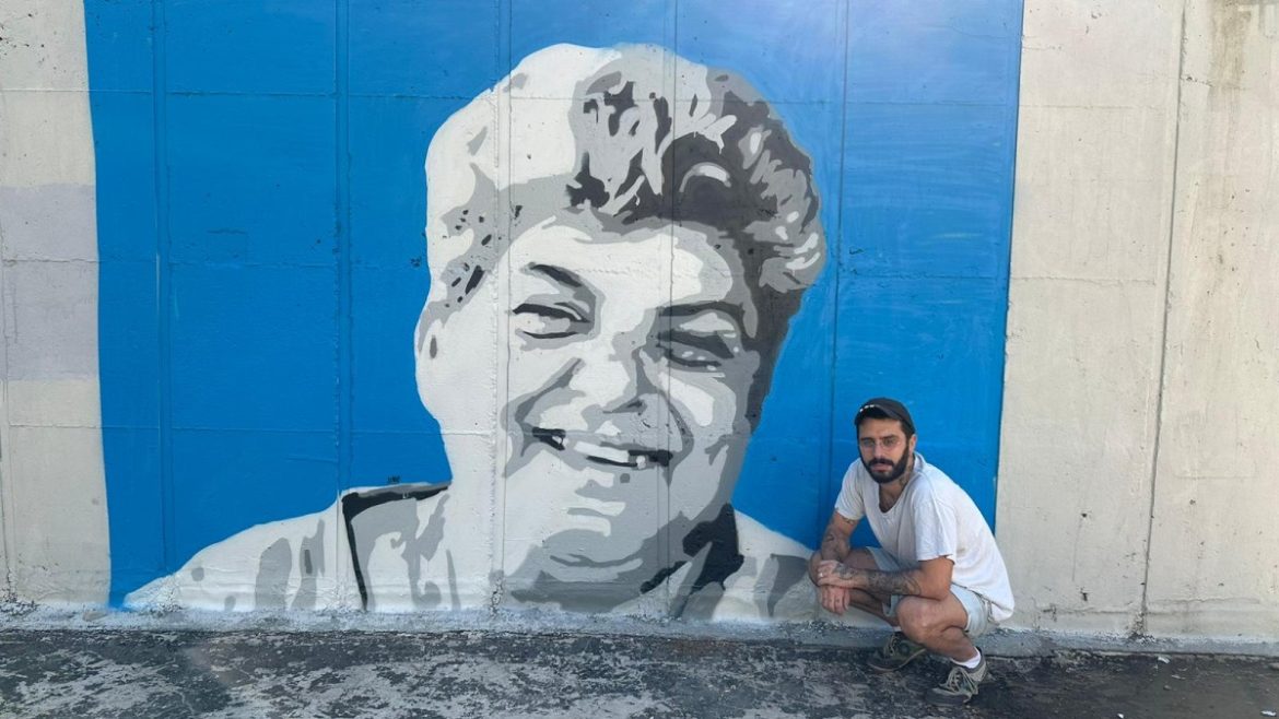 האמן החיפאי עדי יונתן כהן וציור הקיר של רחל אדרי בנווה שאנן (צילום: דוברות עיריית חיפה)